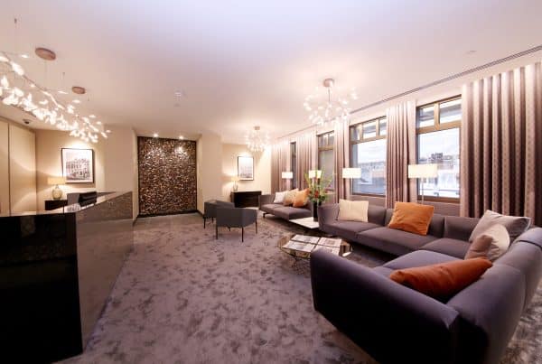 Contemporary office lounge reception area with stylish sofas, accent lighting, textured feature wall, and reception desk—demonstrating high-quality interior fit out and bespoke refurbishment for commercial spaces.