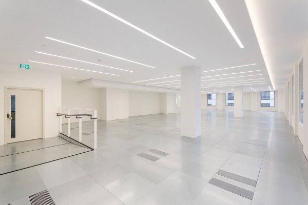1-23 Contemporary office interior with bright finishes, energy-efficient HVAC system integrated into the flooring, and automated lighting for a flexible workspace.