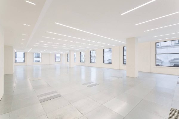1-28 Modern refurbished office floorplate with expansive windows, clean white finishes, and energy-efficient underfloor ventilation panels beneath a minimalist ceiling design.