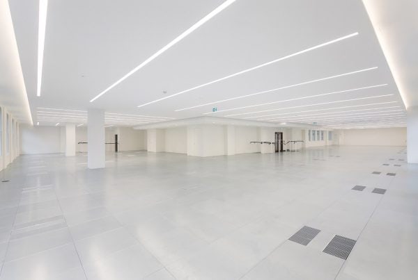 Spacious CAT A office interior showcasing advanced underfloor air distribution, intelligent lighting strips, and a neutral color palette for a contemporary workspace.