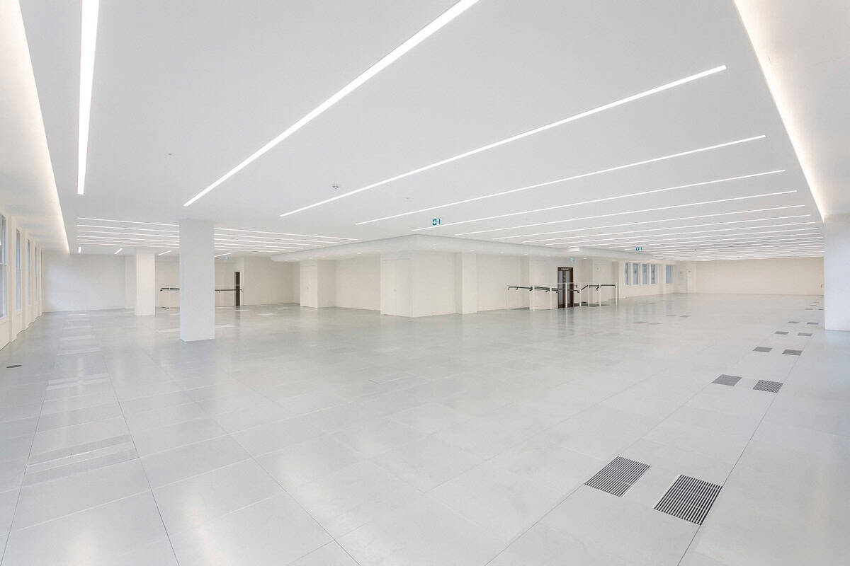 Spacious CAT A office interior showcasing advanced underfloor air distribution, intelligent lighting strips, and a neutral color palette for a contemporary workspace.