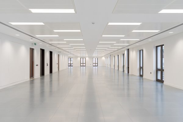 Modern refurbished office level showcasing new lighting, smooth grey flooring, crisp white finishes, and updated window frames throughout