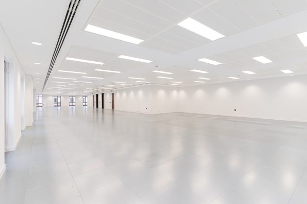 Bright refurbished office floor featuring new suspended lighting, pristine white ceilings, contemporary grey flooring, and upgraded perimeter windows.