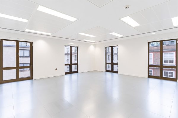 Refurbished corner office space with fresh grey flooring, clean white walls, and large renewed windows providing daylight and city views.