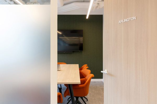 Refurbished meeting suite with timber door signage, upgraded décor, and bright orange seating visible inside as part of a high‑quality office fit‑out.