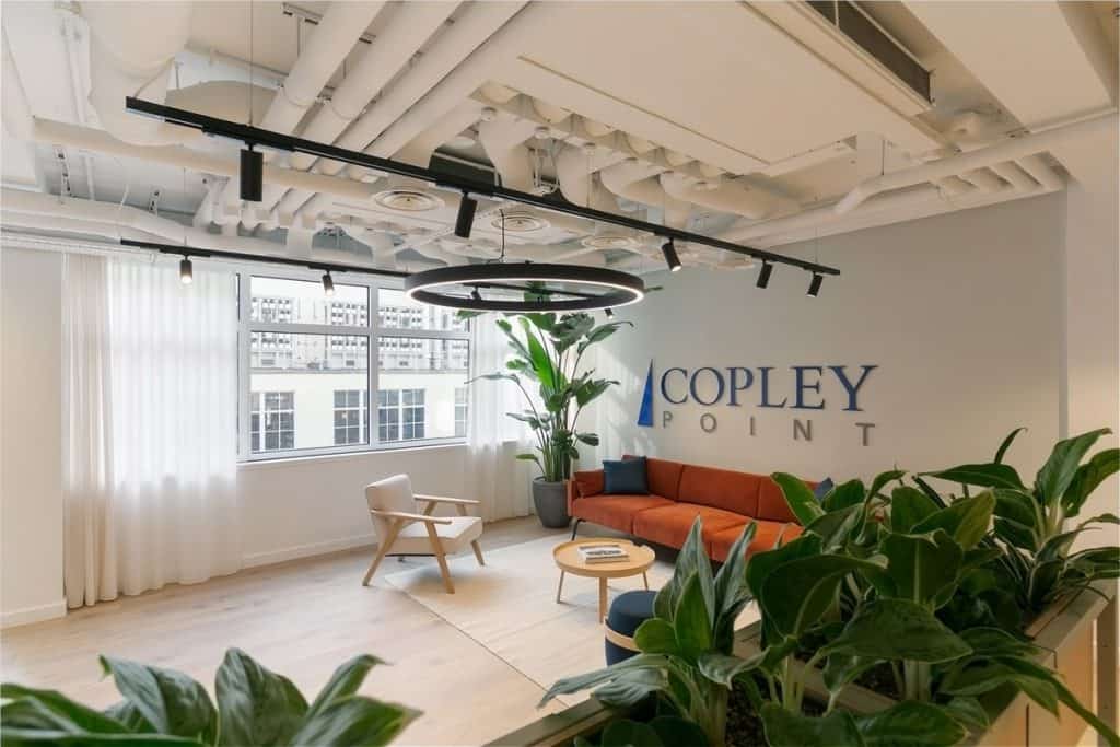 Bright and modern reception space featuring new timber flooring, soft seating, large plants, and overhead feature lighting installed as part of the office refurbishment.