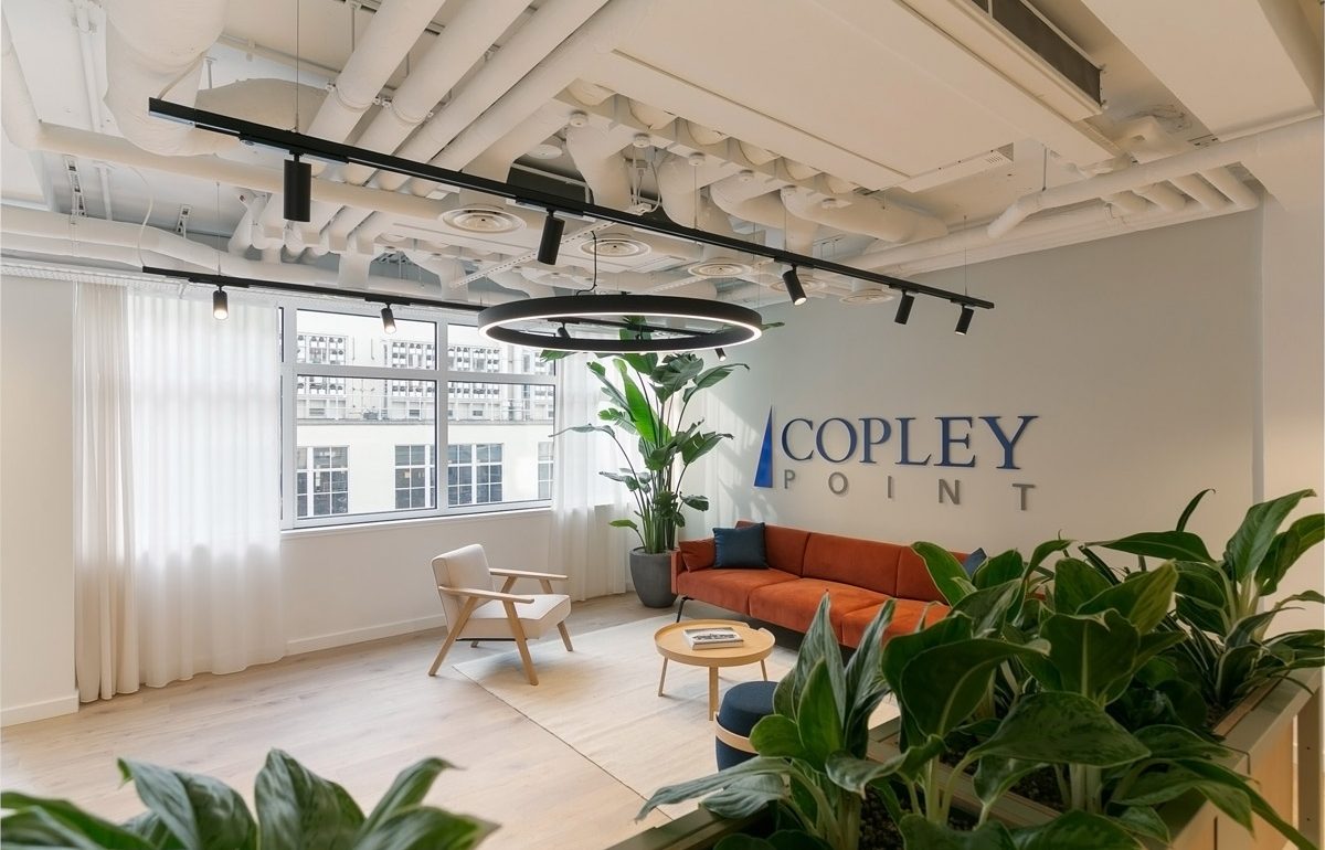 Bright and modern reception space featuring new timber flooring, soft seating, large plants, and overhead feature lighting installed as part of the office refurbishment.