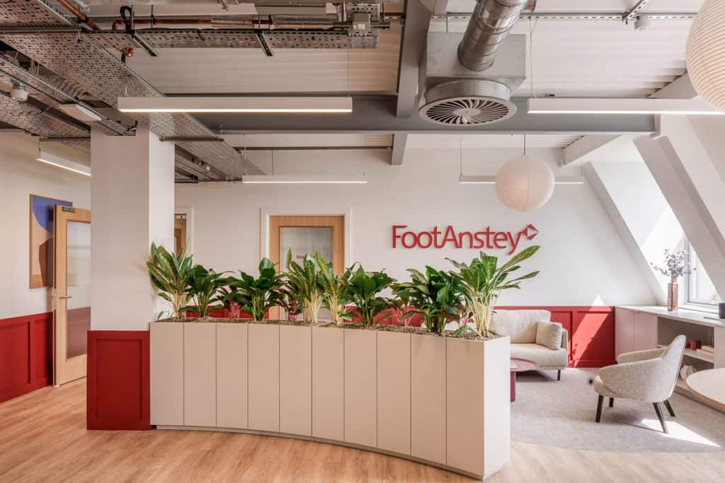 CAT B office fit out reception area with branded Foot Anstey wall, integrated planter joinery, soft seating and exposed services ceiling.