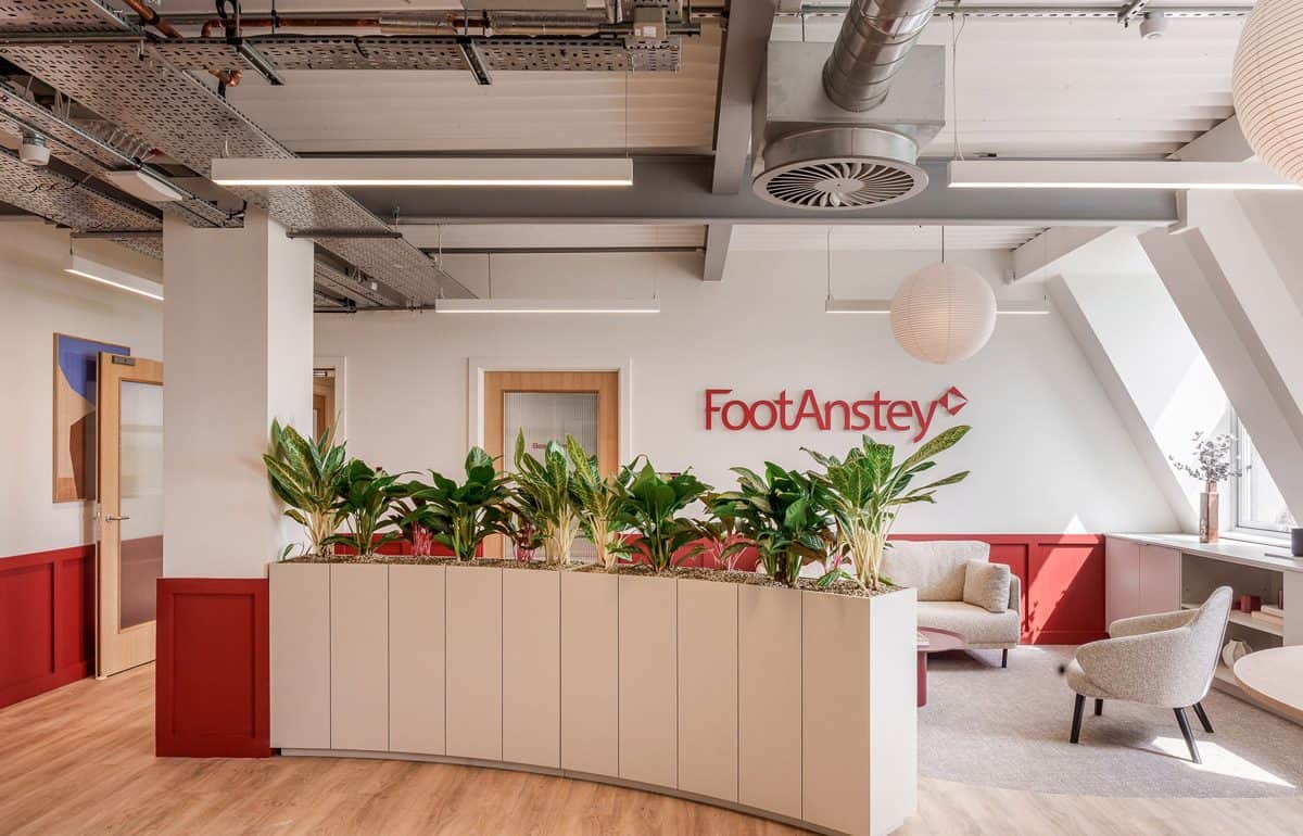 CAT B office fit out reception area with branded Foot Anstey wall, integrated planter joinery, soft seating and exposed services ceiling.