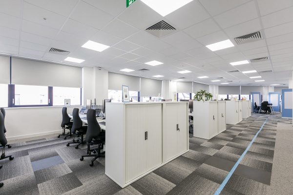 Open plan office workspace with bench desking, storage units, carpet tiles and enhanced lighting and ventilation systems installed during CAT B fit out.
