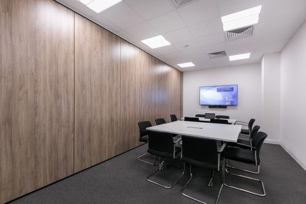 Meeting room with veneered wall finish, integrated AV screen, data connectivity and modern furniture within CAT B office fit out environment.